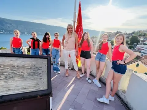 Skupina Arabeske na terasi z mentorico in rdečo zastavo