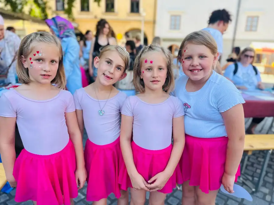 Štiri mlade plesalke z risanimi srci na licu na mestnem dogodku